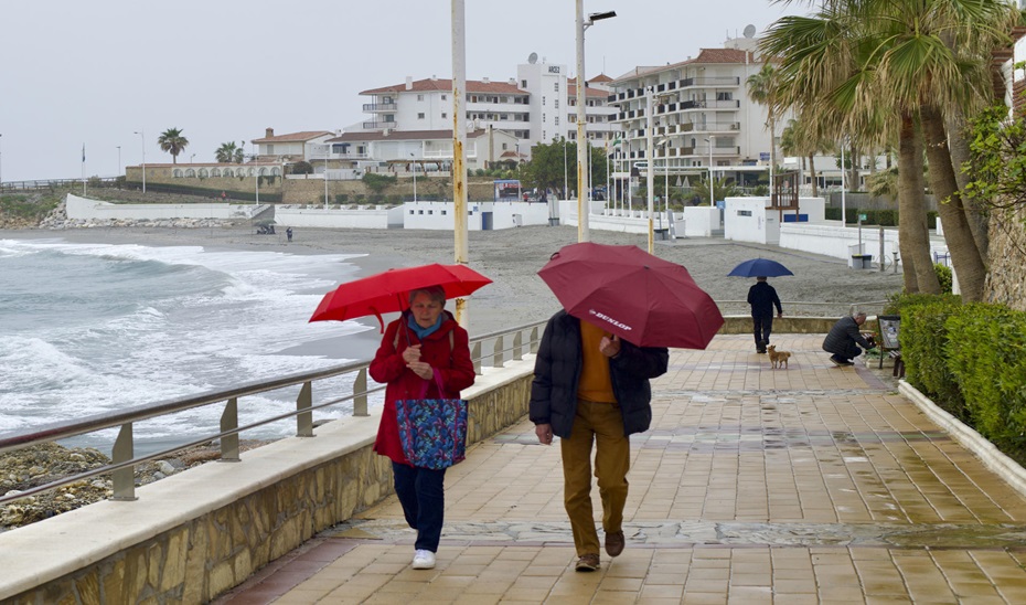 Una pareja camina por el paseo marítimo de la playa de la Torrecilla en Nerja, este domingo, donde continúa lloviendo. EFE/Jose Manuel Pedrosa